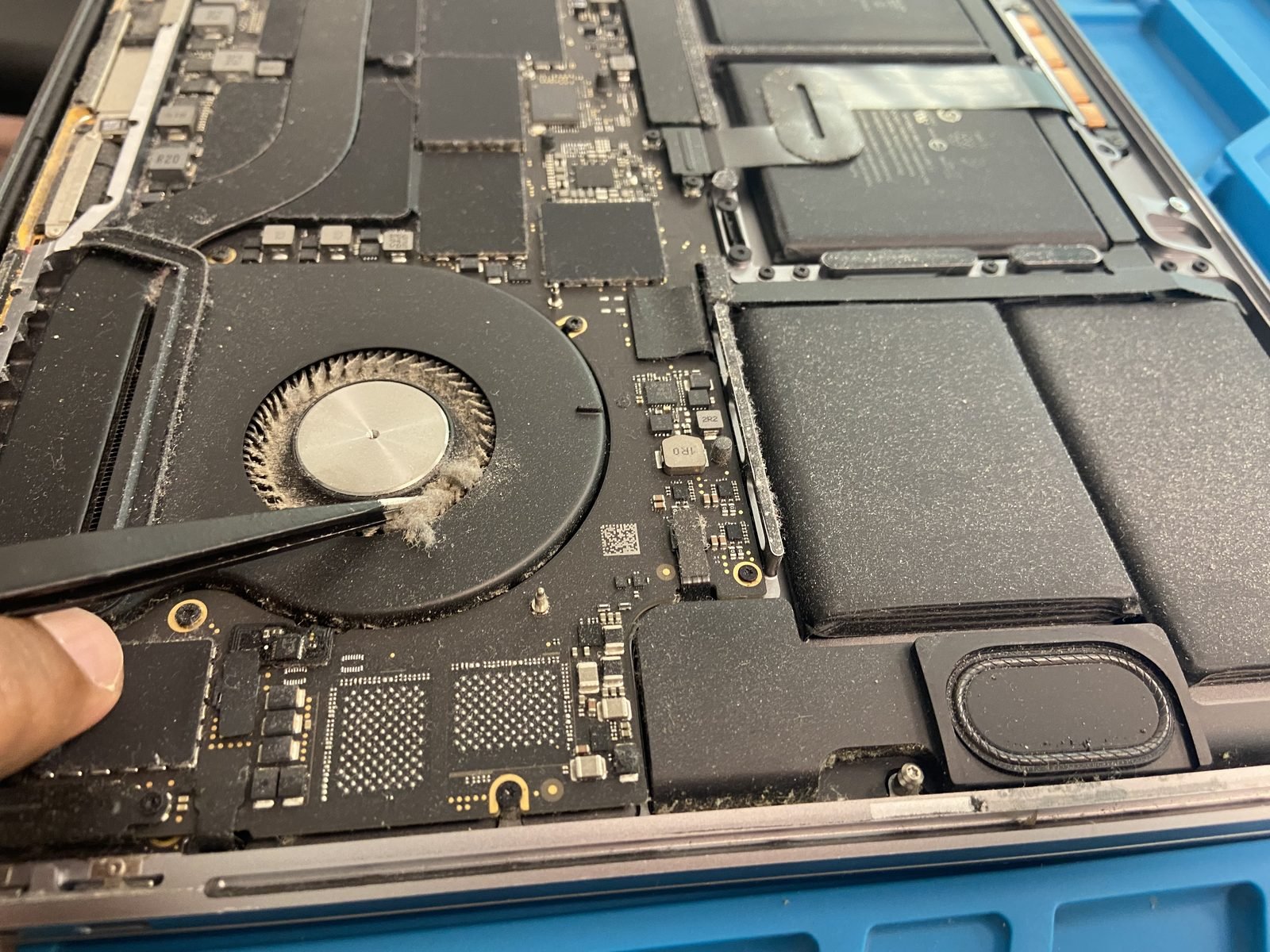 MacBook logic board and fan repair in Dubai MacBook Repair Dubai technician servicing a MacBook Pro cooling fan and logic board at the Media City workshop